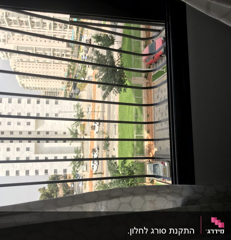 סורגי חלון עם וילון לבן בחלק התחתון